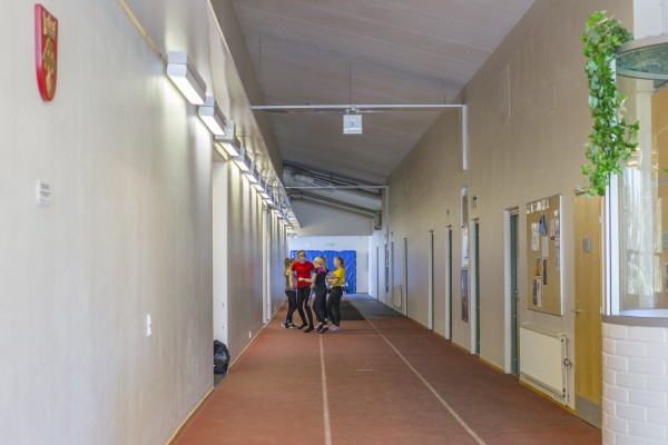 Upplyst korridor i idrottshallen där ett gäng med ungdomar förbereder sig inför träning.