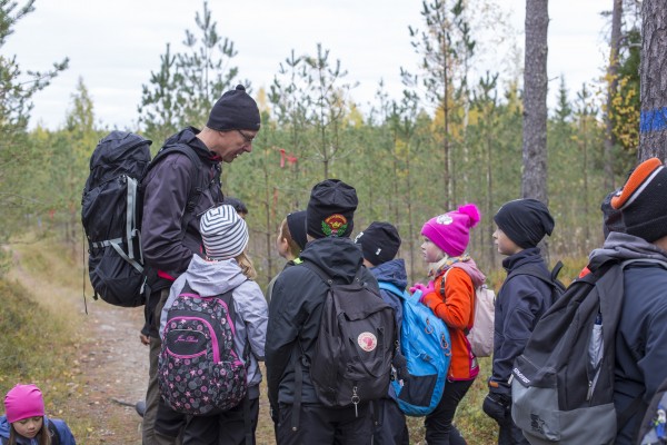 Lapset lähdössä opettajan kanssa syksyiseen metsään vaeltamaan.