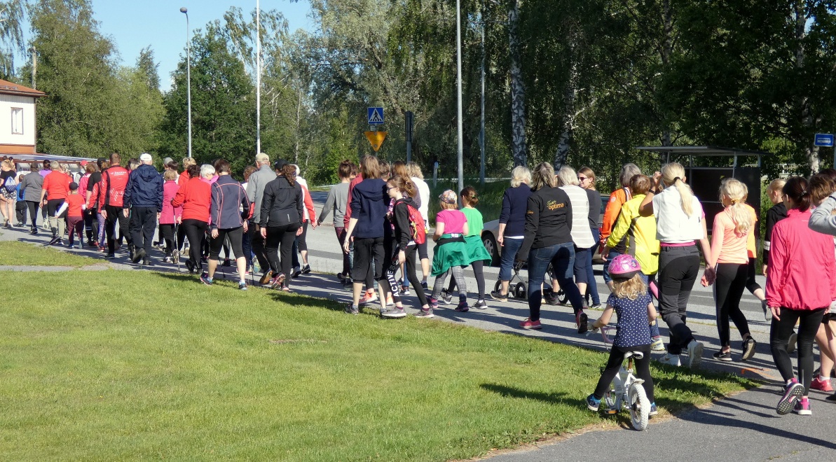 Tiotals människor går efter varandra på väg runt Krombirundan en vacker sommardag.