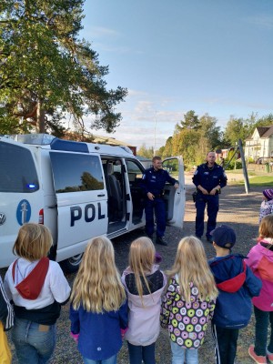 Poliser står utanför polisbilen och berättar om sitt arbete för eleverna i skolan.