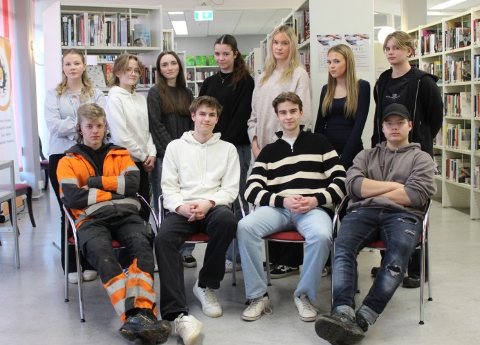 Nuorisovaltuuston jäsenet hymyilevät kuvassa kirjastossa.